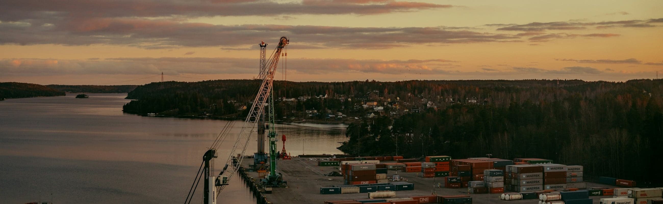 Container port at dusk, cranes and stacked shipping containers